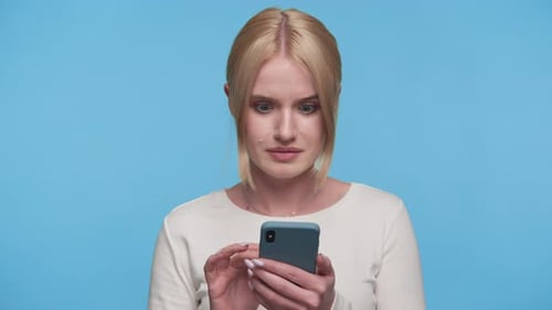 Woman Using Mobile Phone Displays Shocked Facial Expression