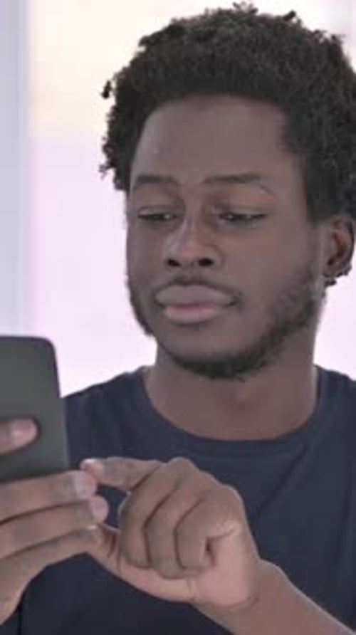 Young Man Using Mobile Phone in Home