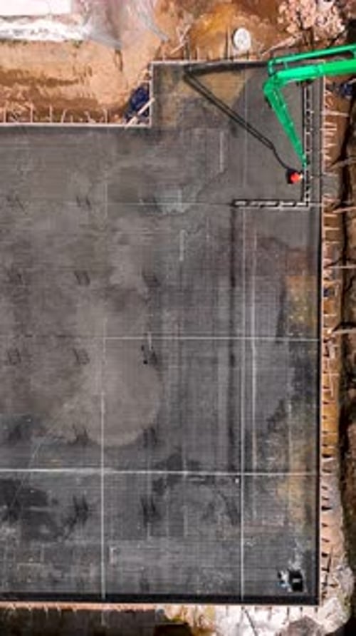 Vídeo vertical Los constructores y las máquinas trabajan rápidamente en una obra de construcción capturada en un impresionante