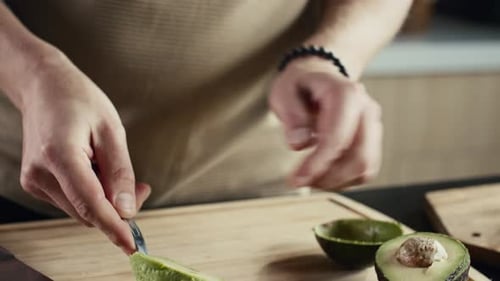 Person Slicing Avocado on Cutting Board in Kitchen