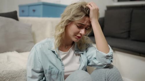 Distressed Woman Sitting on Living Room Floor