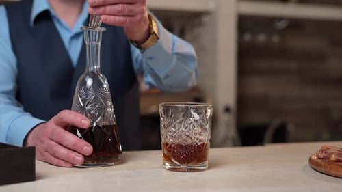Manos del camarero, que saca la botella de whisky de la barra del bar