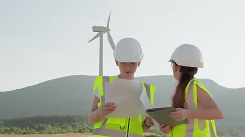 Engineers Review Wind Turbine Operations Onsite Ensuring Safety with Highvisibility Vests and