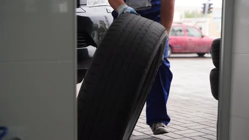Auto Mechanic at Tire Shop Replaces Car Wheels Inspects Treads Services Vehicle with Tools Checks