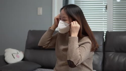 Young Adult Putting On Face Mask Indoors