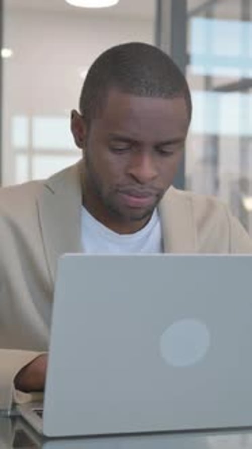 African Businessman Working on Laptop in Office, vertical video