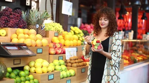 Mujer disfrutando de ensalada de fruta fresca en el puesto del mercado
