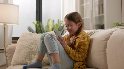 Child Using Smartphone on Couch in Home