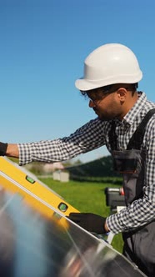 Muslim Technician Installing Solar Panel with Spirit Level