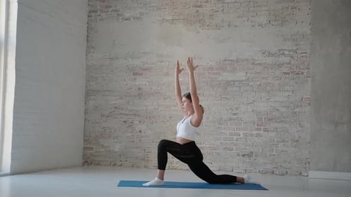 Young Woman Practicing Yoga and Stretching on Mat