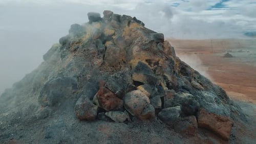 Volcanic rock fumarole releasing hot steam and sulfurous gas in a geothermal area in Iceland