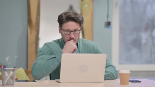 Adult Man Concentrating at Laptop in Office
