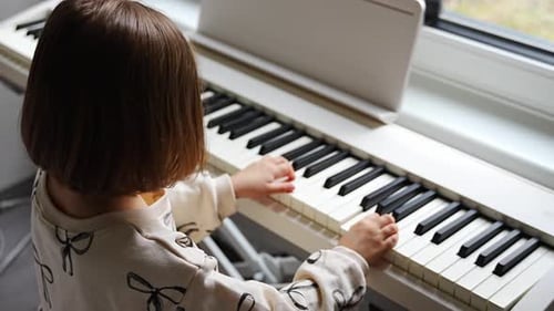 Child Plays Piano Indoors During the Daytime
