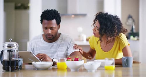 Woman Talking to Man Using Tablet at Breakfast