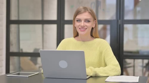 Blonde Woman Smiles at Desk with Laptop