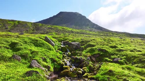 Mountains Covered With Green Moss And Grass On A Sunny Day Small River Flows Down The Slope