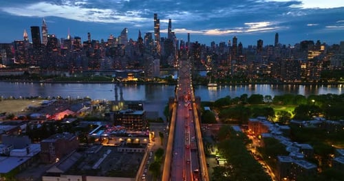 Stunning view of the city at coming evening. Queensboro Bridge in lights with cars passing along.