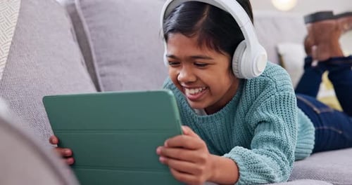 Laughing Child Using Tablet with Headphones at Home