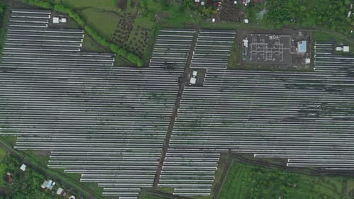 High altitude aerial view of a vast solar farm with rows of photovoltaic panels, showcasing a large