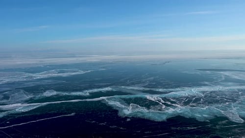 On the surface of the frozen lake, many white cracks. Camera moves horizontally.