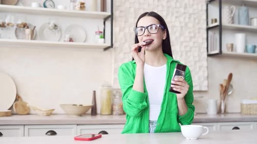 Woman Enjoys Eating Chocolate in Kitchen