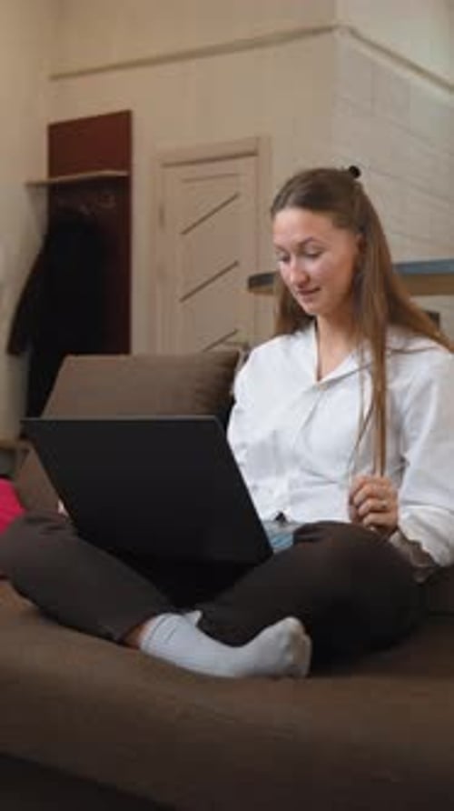 Young woman having online conversation on laptop at home