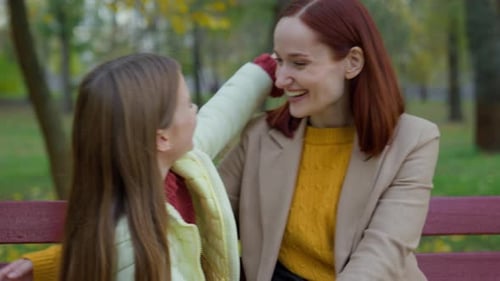 Mother and Daughter Hugging on Bench in Park
