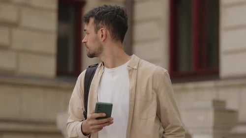 Young Man Using a Cellphone in the City Exploring Urban Areas and Navigating with Technology