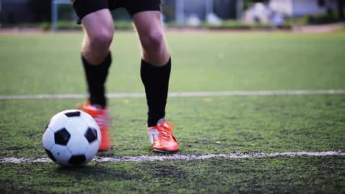 Soccer player kicks ball on field during football game training