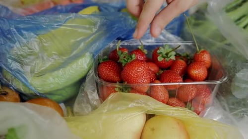 Los plátanos, las fresas y las peras están sobre la mesa en bolsas de plástico