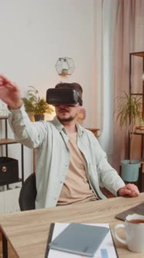 Confident Young Caucasian Man Freelancer Using VR Headset While Sitting at Home Office Table Desk
