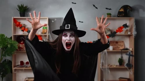 Creepy Vampire Witch Makes a Frightening Gesture in a Halloween Room