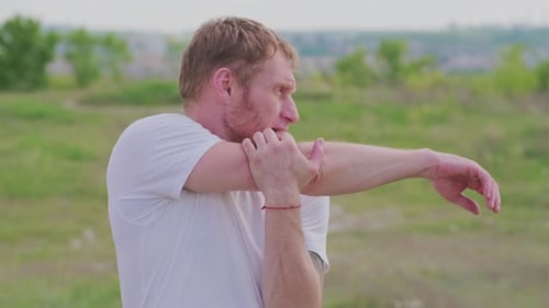 Man Stretching Arms Outdoors in Field