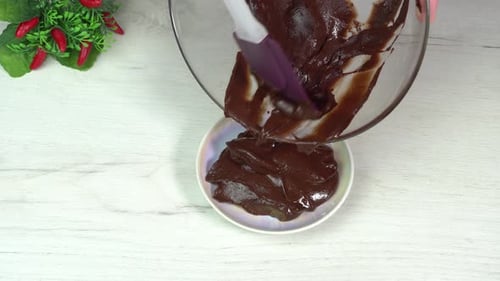 Schokolade von Hand aus einer Glasschüssel mit einem Spatel in einen Teller gießen, um ein Dessert zuzubereiten. Muffin kochen