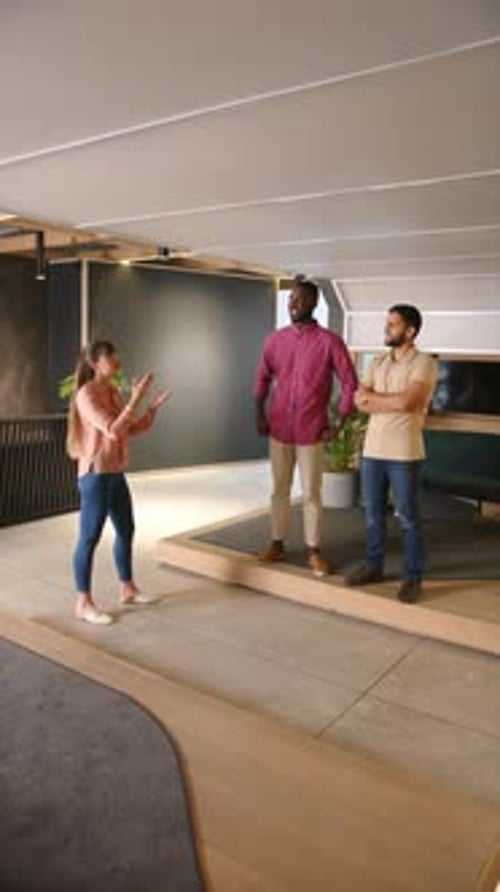 Vertical video: Discussing project, diverse business team standing and talking in modern office