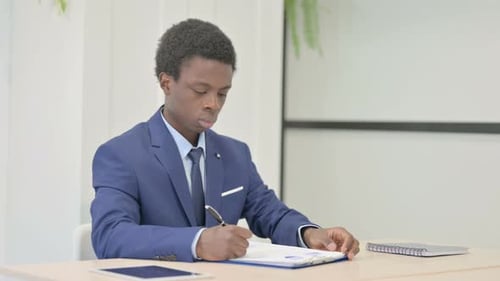 African Businessman Doing Paperwork in Office