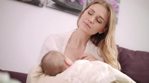 Woman Breastfeeding Baby on Couch Indoors