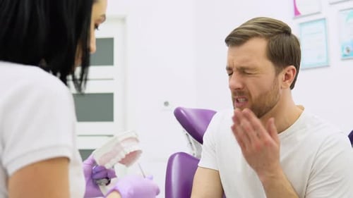 Man Experiencing Toothache Consulting with Dentist in Clinic