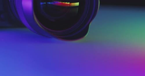 Camera with lens in colorful luminous surroundings on the table