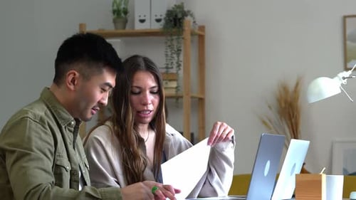 Young Adults Working Together at Desk with Laptops