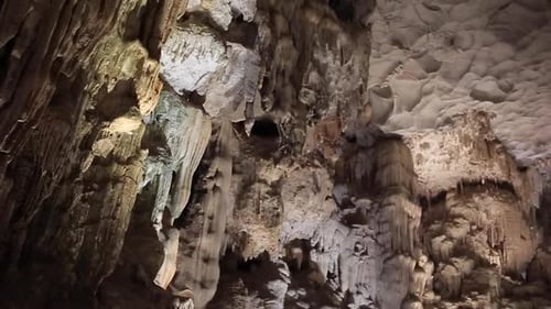 Cave limestone underground with white stalactites and stalagmites. Panning rotation slow motion view