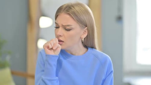 Woman Coughing, Touching Sore Throat Indoors