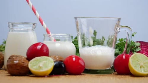 Un vaso de leche y verduras sobre una mesa, junto con otros ingredientes. Leche y verduras