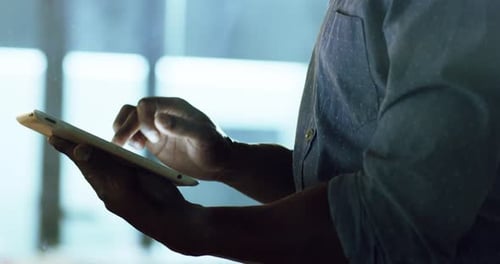 4k video footage of an unrecognizable businessman using a digital tablet at night in an office