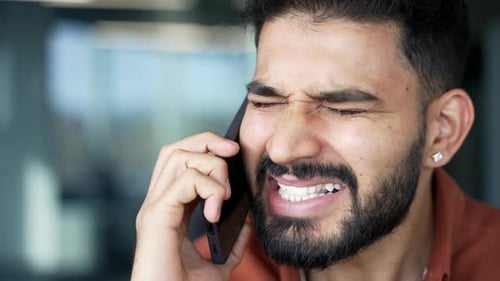 Angry businessman arguing talking on mobile phone sitting at workplace in office. Nervous boss scold