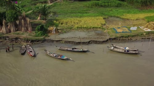 Aerial view of people working along the river on wooden boats.