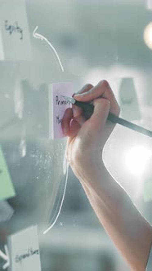 Glass wall, hand and sticky notes with business person in office for brainstorming or strategy