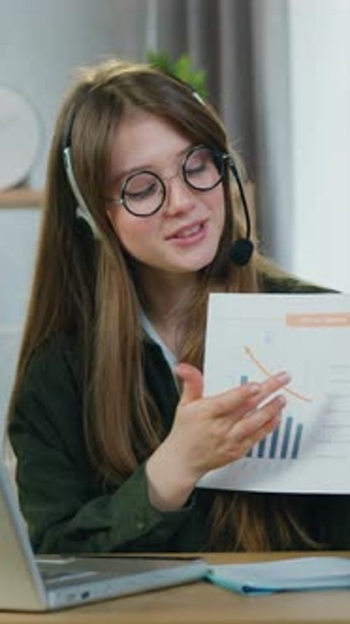 Lovely Woman in Wireless Headphones Holding Online Meeting with Coworkers on Laptop From Home Office