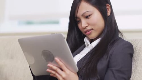 Smiling asian businesswoman uses digital tablet in modern office lobby