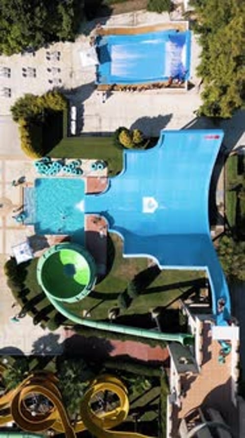 Aerial View of a Colorful Water Park with Multiple Slides Pools and People Enjoying Summer